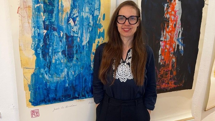 Die Berliner Künstlerin Natalie Fellhauer steht vor zwei ihrer Werke der Ausstellung