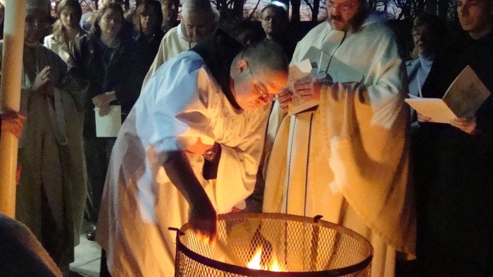 People in robes gather around a fire pit.