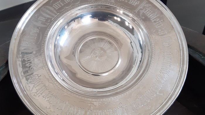 Silberner Pokal mit eingravierten Buchstaben auf einem Tisch