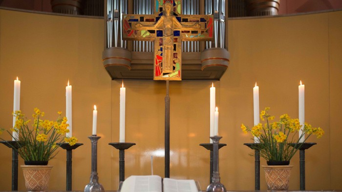 Kirchenaltar mit Kerzen, Blumen und einem aufgeschlagenen Buch