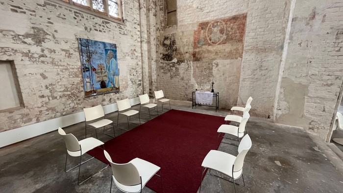 Ein moderner Konferenzraum mit weißen Stühlen und einem roten Teppich in einem alten, verfallenen Gebäude.