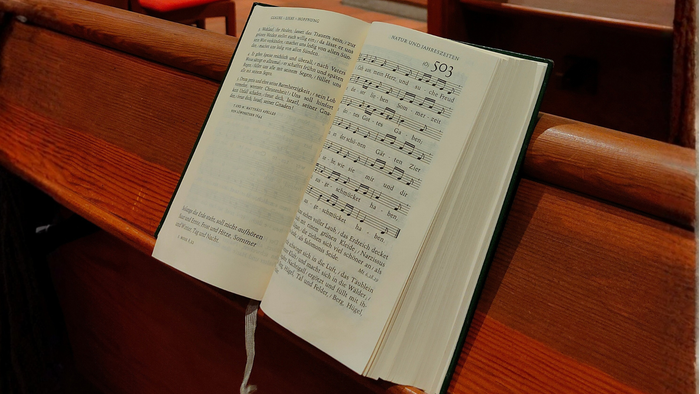Foto von einem aufgeschlagenen Gesangbuch in einer Kirchenbank