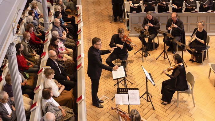 Ein klassisches Streichensemble spielt für ein aufmerksames Publikum in einem historischen Innenraum.