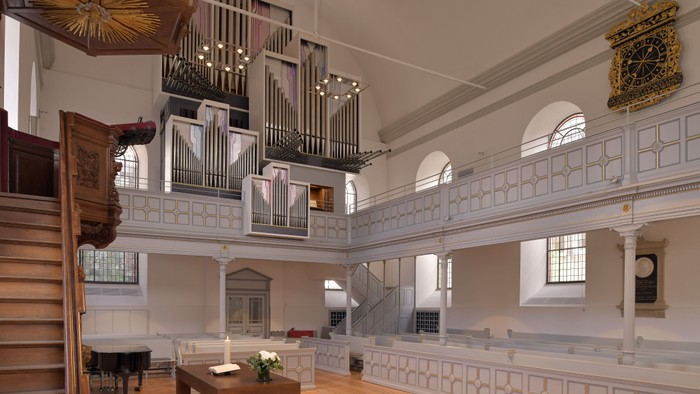 Eleganter Kircheninnenraum mit einer prächtigen Orgel, hölzernen Kirchenbänken und klassischen architektonischen Details.