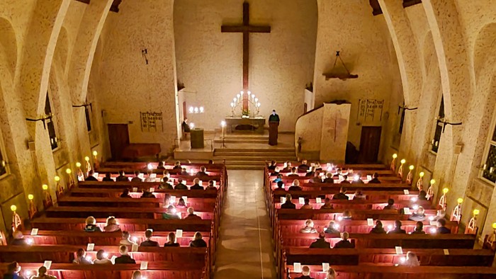 Innenraum einer Kirche mit Holzbänken und Kreuz