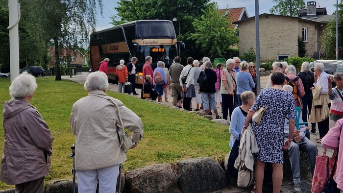 En gruppe mennesker står i en kreds på en stenlagt plads i en park.