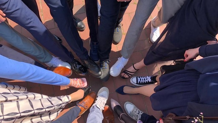 Menschen, die im Kreis stehen und ihre Füße und Schuhe zeigen.