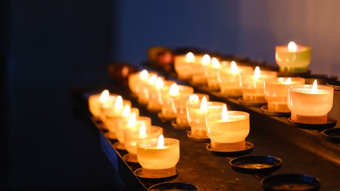 Eine Reihe von brennenden Kerzen in weißen Gefäßen auf einem Tisch