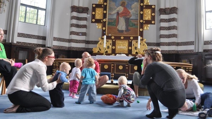 En gruppe voksne og børn i kirke foran altertavle
