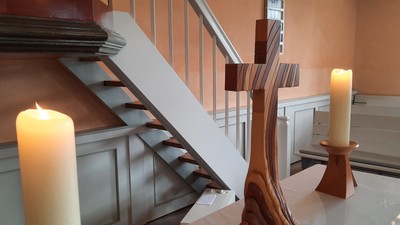 Kerzen und hölzernes Kreuz auf Stufen