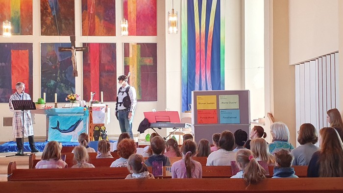 Ein Gottesdienst mit Kindern, die an einer Lektion oder Aktivität teilnehmen, geleitet von Geistlichen und Ehrenamtlichen.