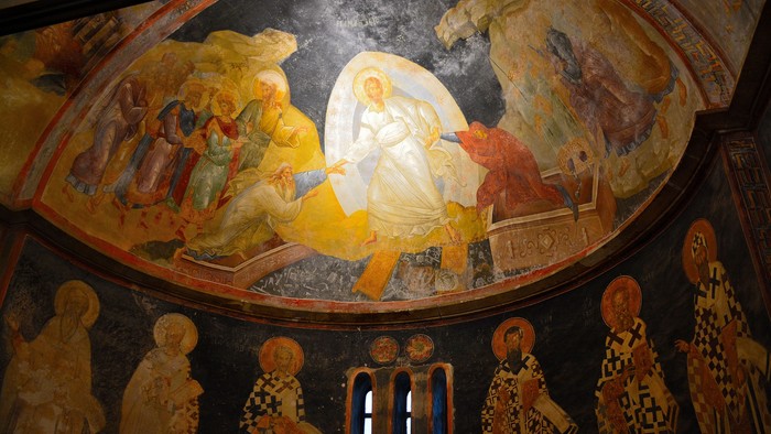Livfuld fresko, der afbilder religiøse figurer i en kuppelhvælving med helgener og himmelske scener.