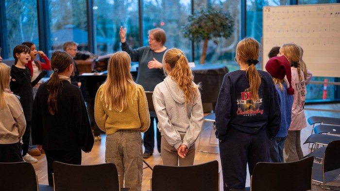 En gruppe af elever står i en klassesal og ser ud af et stort vindue.