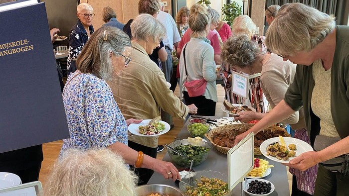 Mennesker ved buffet - med Højskolesangbog i forgrunden