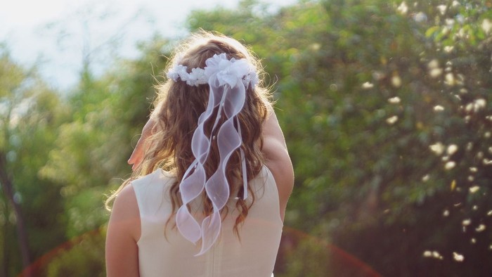 En kvinde med hårbånd står i en trækirkegård