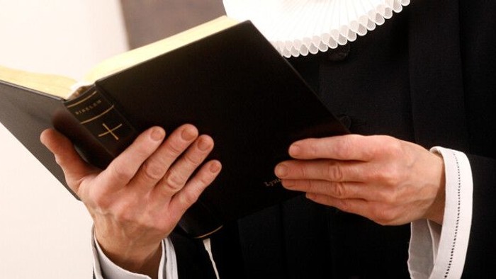 En person i svart og hvid tøj holder en bibel.