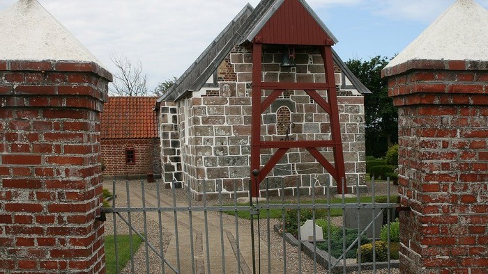 En murstensmur med to tårn og en smedje med røde og hvide elementer.