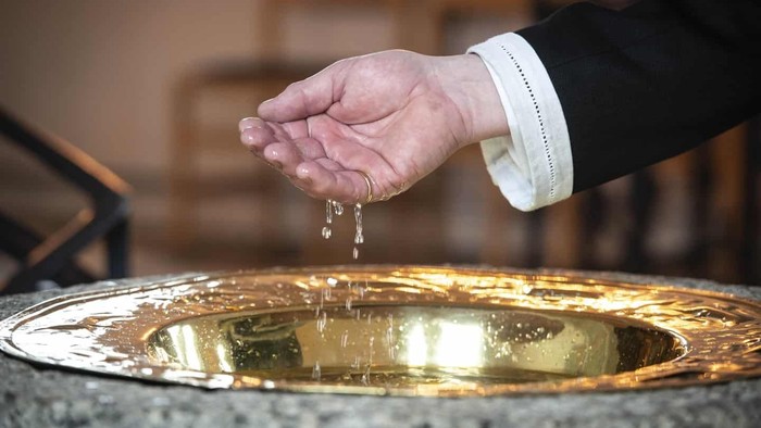 Hånd tager vand ud af gylden forgyldt fontæne.