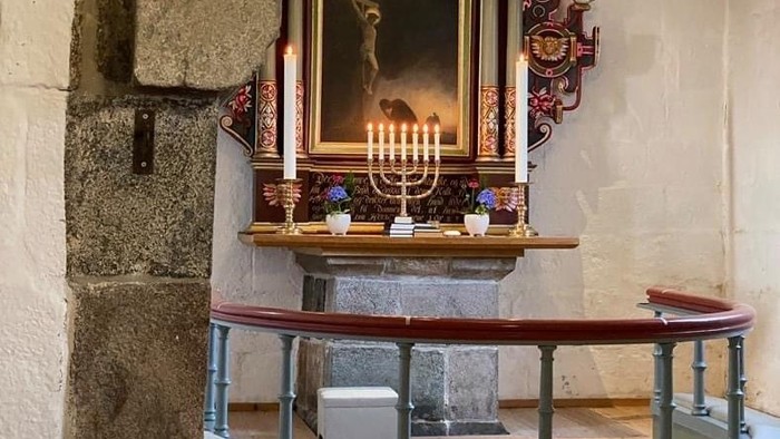 En lille kapel med alter, lysestage og bænke.