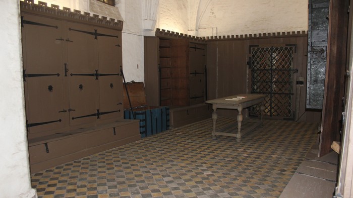 Der Raum hat einen Schachbrettboden und alte Möbel.