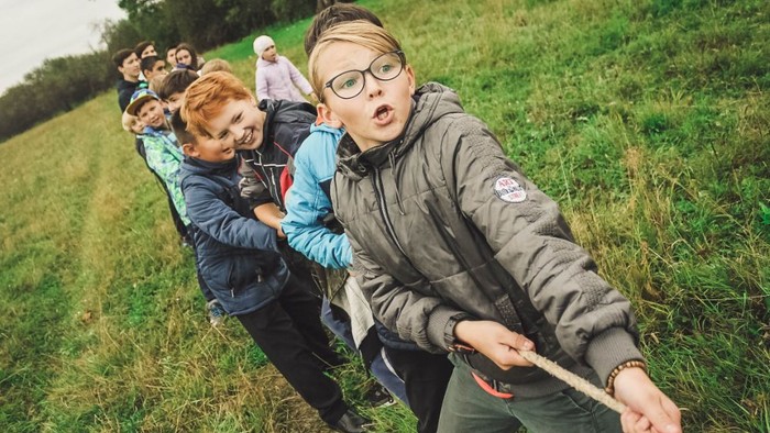 Kinder spielen im Gras energisch Zug um Zug.