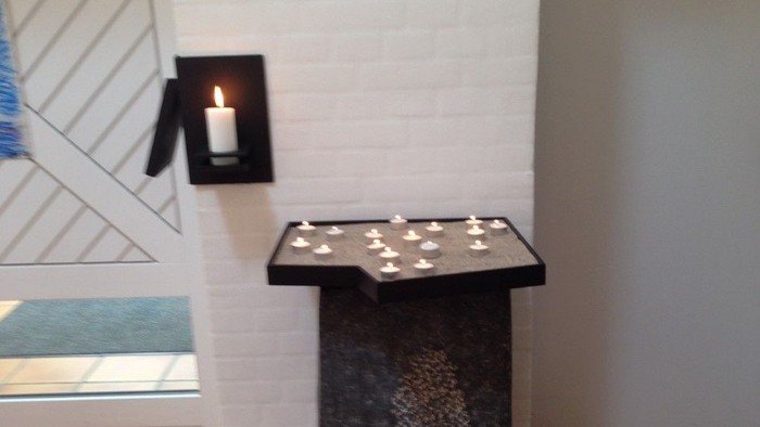 En sort bord med lys på et hvide væg.