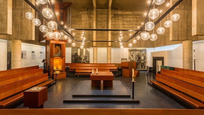 Moderne Kirche mit Holzempore und großen Hängeleuchten
