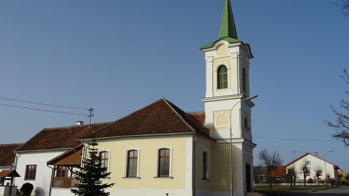 Kleine Kirche mit hohem Turm und grünem Dach in ländlicher Gegend