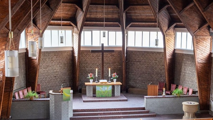 Ein moderner Wohnraum mit hohen Decken und großen Fenstern, eingerichtet mit Holz und grünen Akzenten.