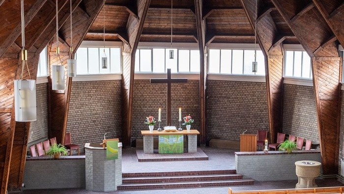 Ein moderner Wohnraum mit hohen Decken und großen Fenstern, eingerichtet mit Holz und grünen Akzenten.