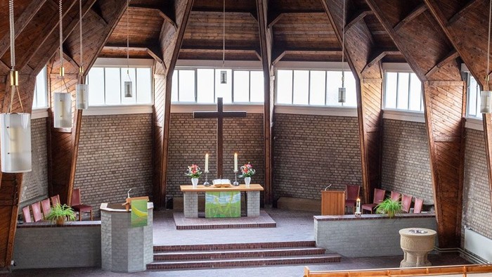 Ein moderner Wohnraum mit hohen Decken und großen Fenstern, eingerichtet mit Holz und grünen Akzenten.