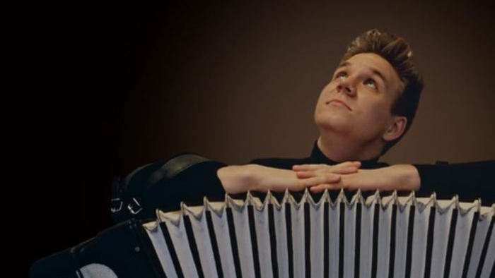 Ein Mann spielt Akkordeon, lehnt sich darauf.