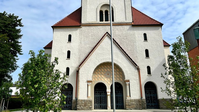 Weiße Kirche mit hohem Glockenturm und rotem Dach.