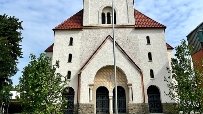 Weiße Kirche mit hohem Glockenturm und rotem Dach.