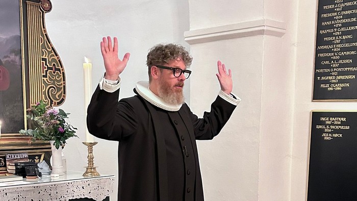 Mand i svart kapittel i kirke.