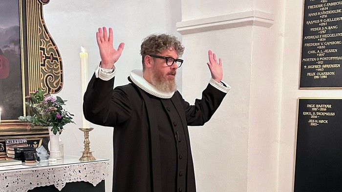 Mand i svart kapittel i kirke.