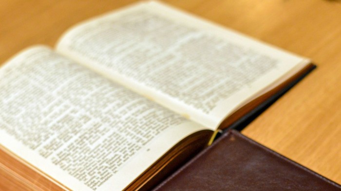 Offenes Buch mit Kreuz auf Einband auf Holzoberfläche