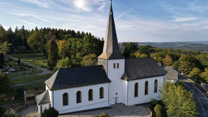 Weiße Kirche mit hohem Turm in ländlicher Umgebung