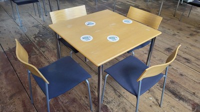 Leerer Holztisch mit blauen Polsterstühlen und Metallgestellen in einem geräumigen Raum.