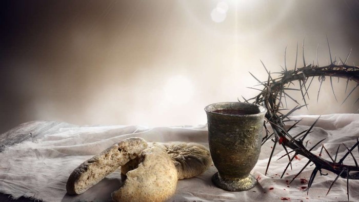 Ein Kelch, eine Dornenkrone und ein Schwamm auf einem Tuch vor einem hellen Hintergrund