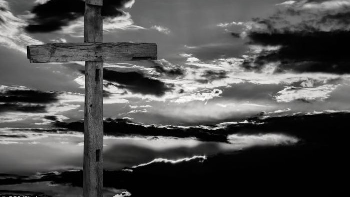 Ein hölzernes Kreuz vor einem dramatischen Wolkenhimmel