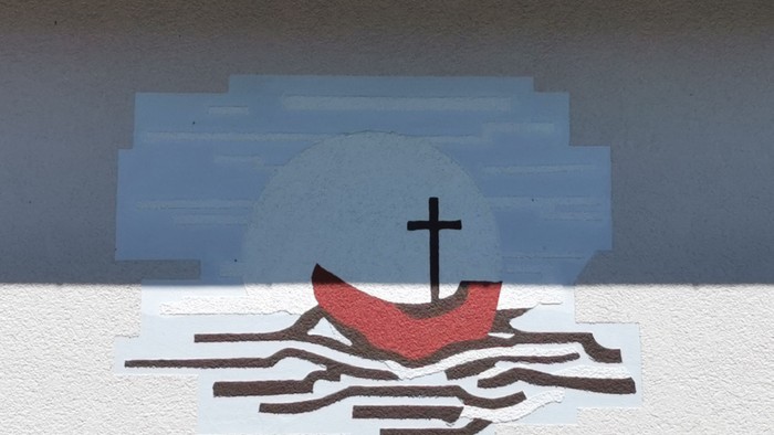 Ein rotes Boot mit Kreuz segelt auf blauem Hintergrund