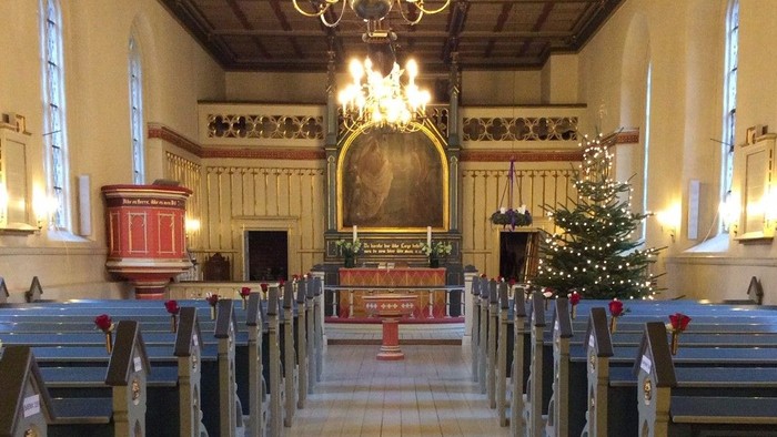 Indre del af kirke med juletræ og bænke.