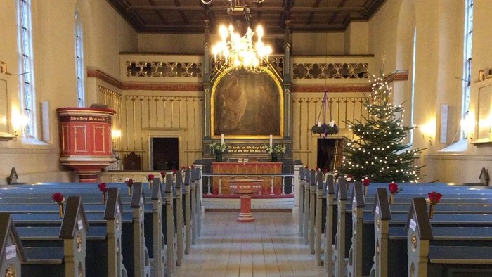 Indre del af kirke med juletræ og bænke.
