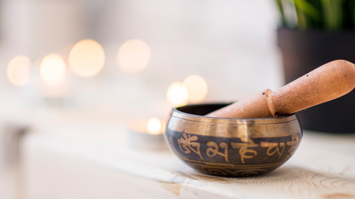 Dekorativer Klangschalen-Set mit Schlägel, Kristallen und Kerzen auf einer ruhigen Oberfläche.