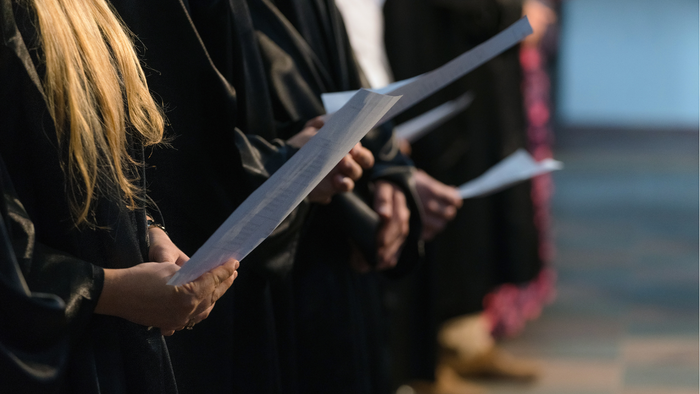 Absolventen mit ihren Diplomen während einer offiziellen Zeremonie im Freien.