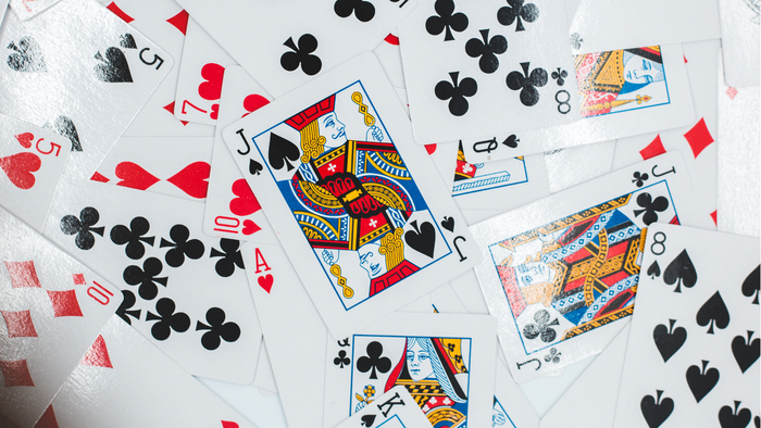 Eine verstreute Ansammlung von Spielkarten mit verschiedenen Farben und Zahlen, die auf einer Oberfläche ausgebreitet sind.