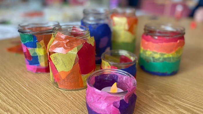 Bunte Glasvasen mit Kerzen auf Holztisch