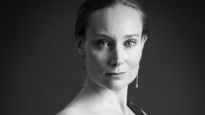 Elegant kvinde i en kjole uden skulderstropper, der poser selvsikkert i et sort-hvidt portræt.