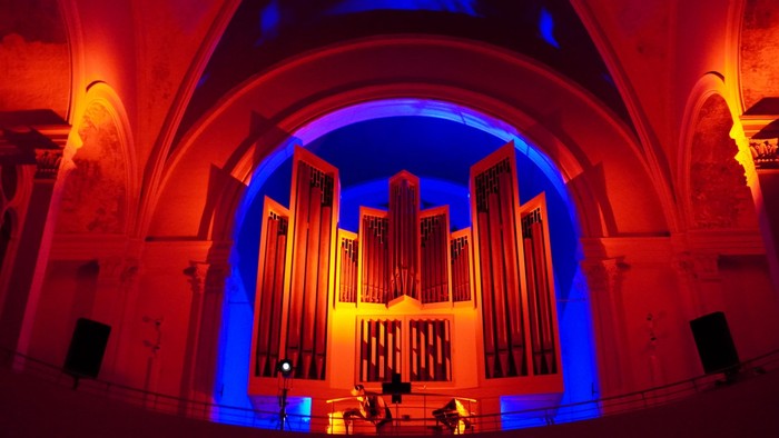 Große Kirchenorgel in einem prächtigen Saal, beleuchtet in warmen und kühlen Farbtönen